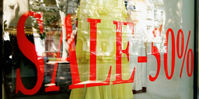 Escaparate con vinilo de rebajas que anuncia un cincuenta por ciento de descuento