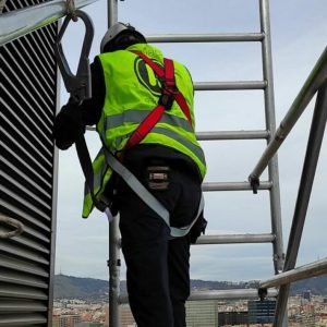 Grafiks installer wearing a safety harness fitting a sign at height