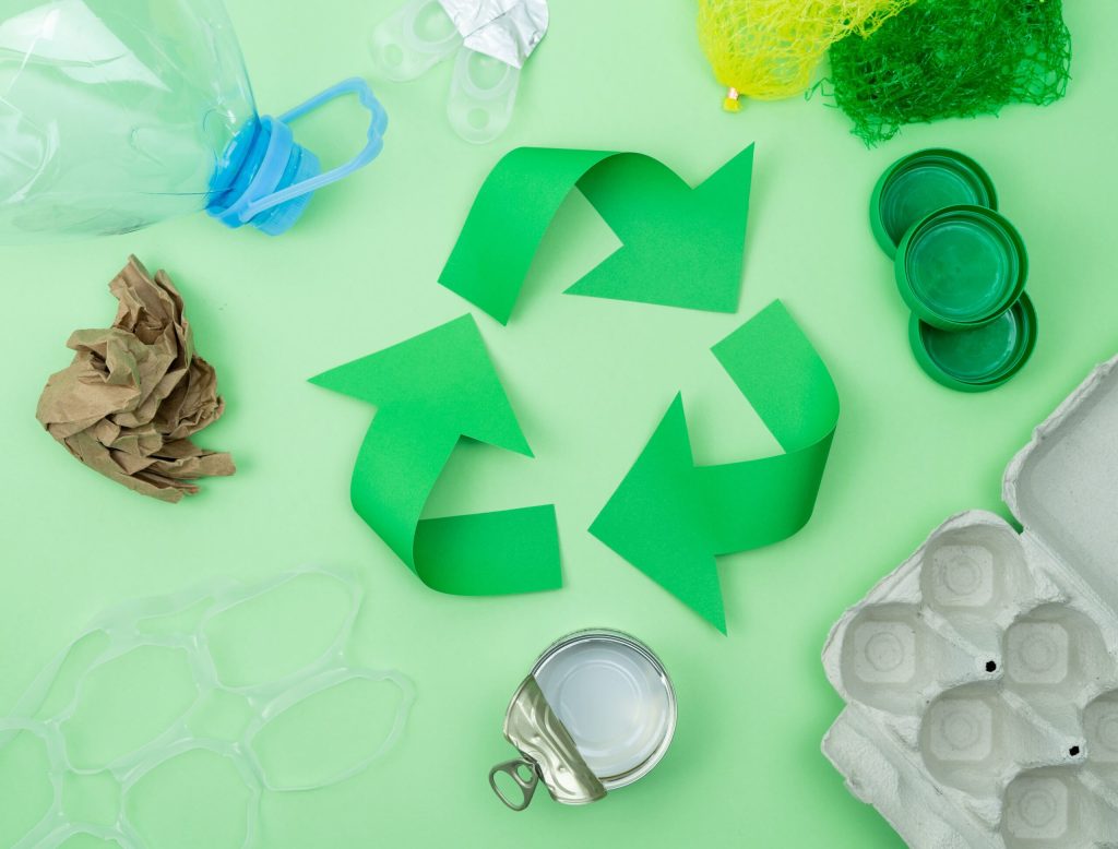 Símbolo de reciclaje verde rodeado de envases y residuos plásticos