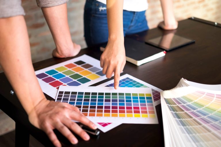 Hands consulting colour charts on a work table