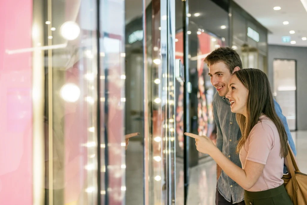 Clientas mirando el escaparate iluminado de una tienda