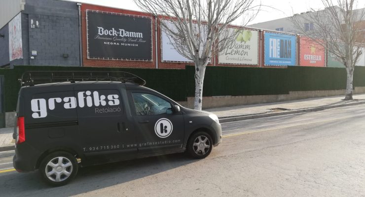 Vehículo de Grafiks aparcado junto a lonas publicitarias de gran formato